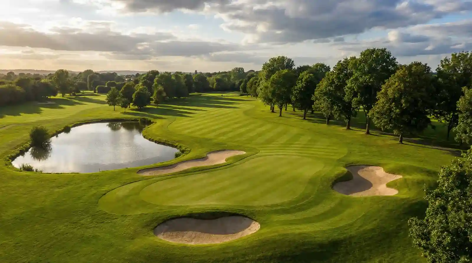 Vista panorámica de un campo de golf con distintos obstáculos: bunkers, agua y árboles